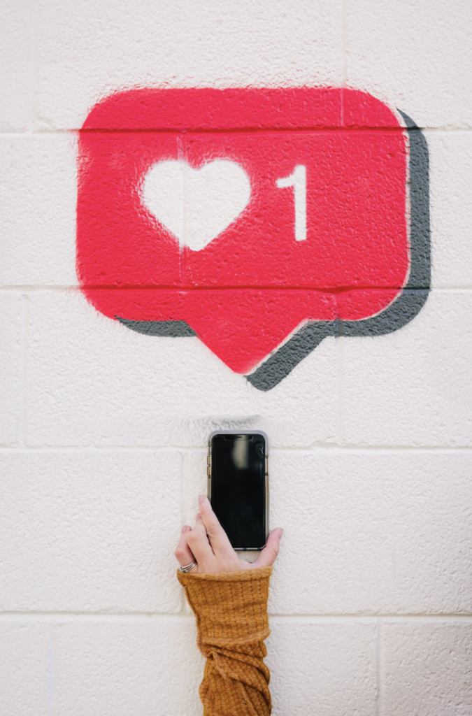 photo with a like symbol and person holding a phone below it
