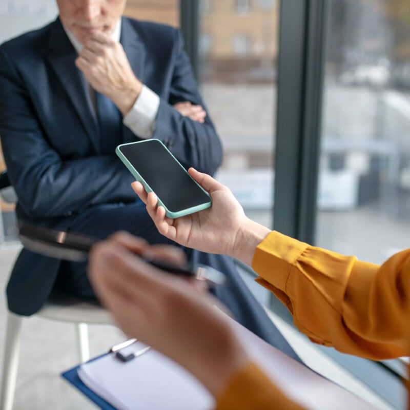 How Many Social Media Apps Should Executives Be On? article banner featuring two office workers on smartphone