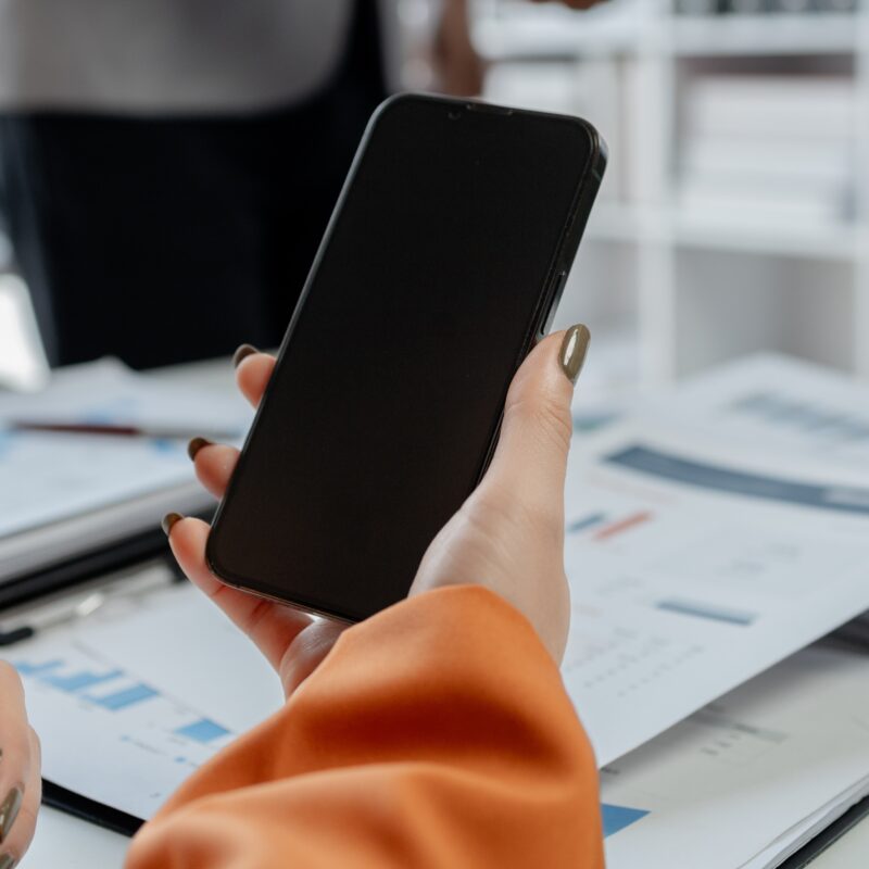 How Often Should Executives Post on Social Media? article banner featuring woman holding smartphone