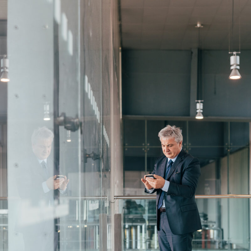 5 Reasons Why CEOs Don’t Want To Be On Social Media article banner featuring senior executive looking at phone